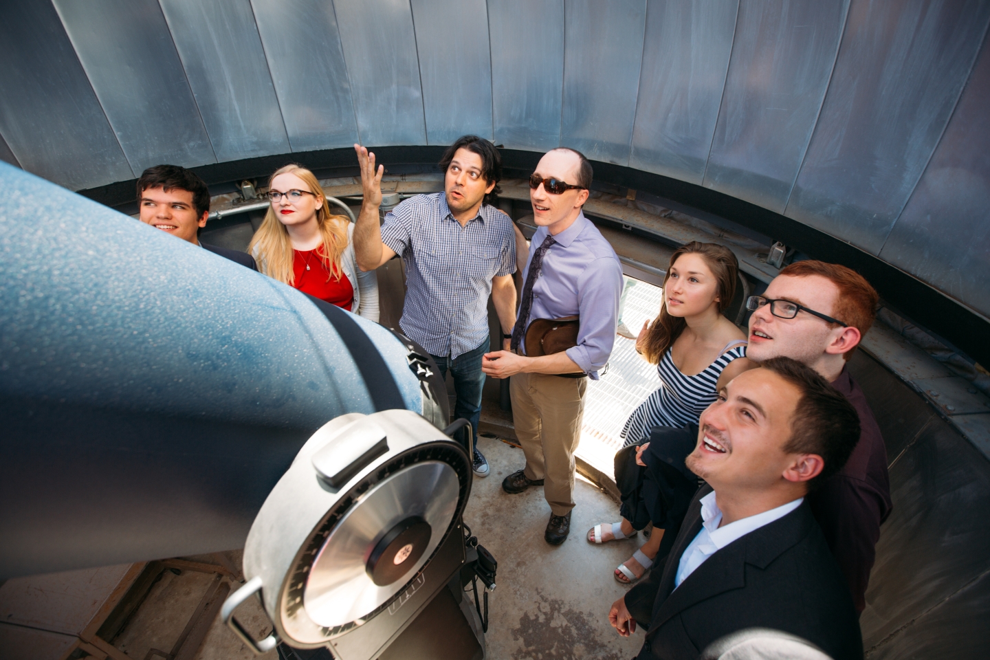 Group of students gazing up large telescope in lab