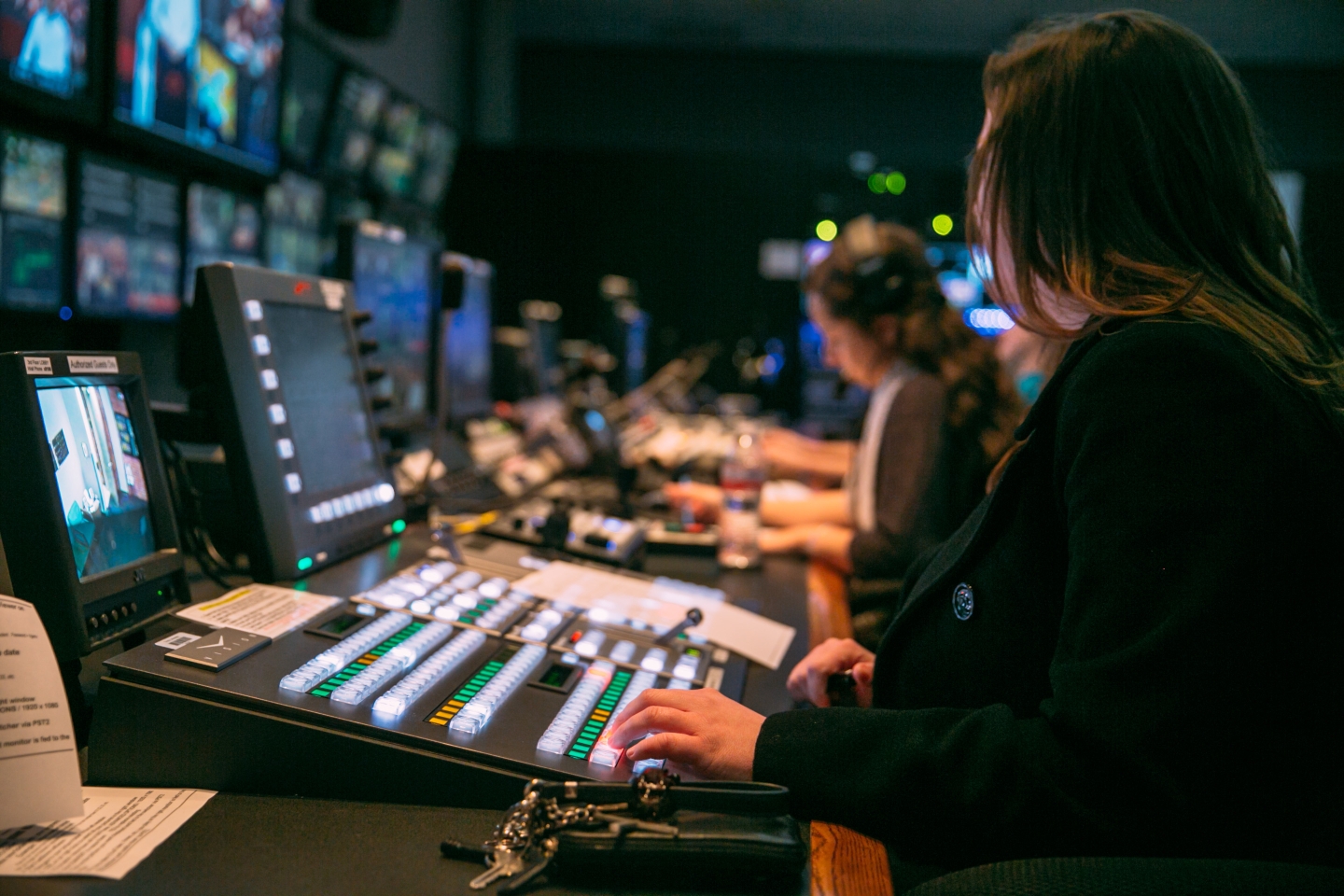 Students working in a tv control room with control boards and monitors