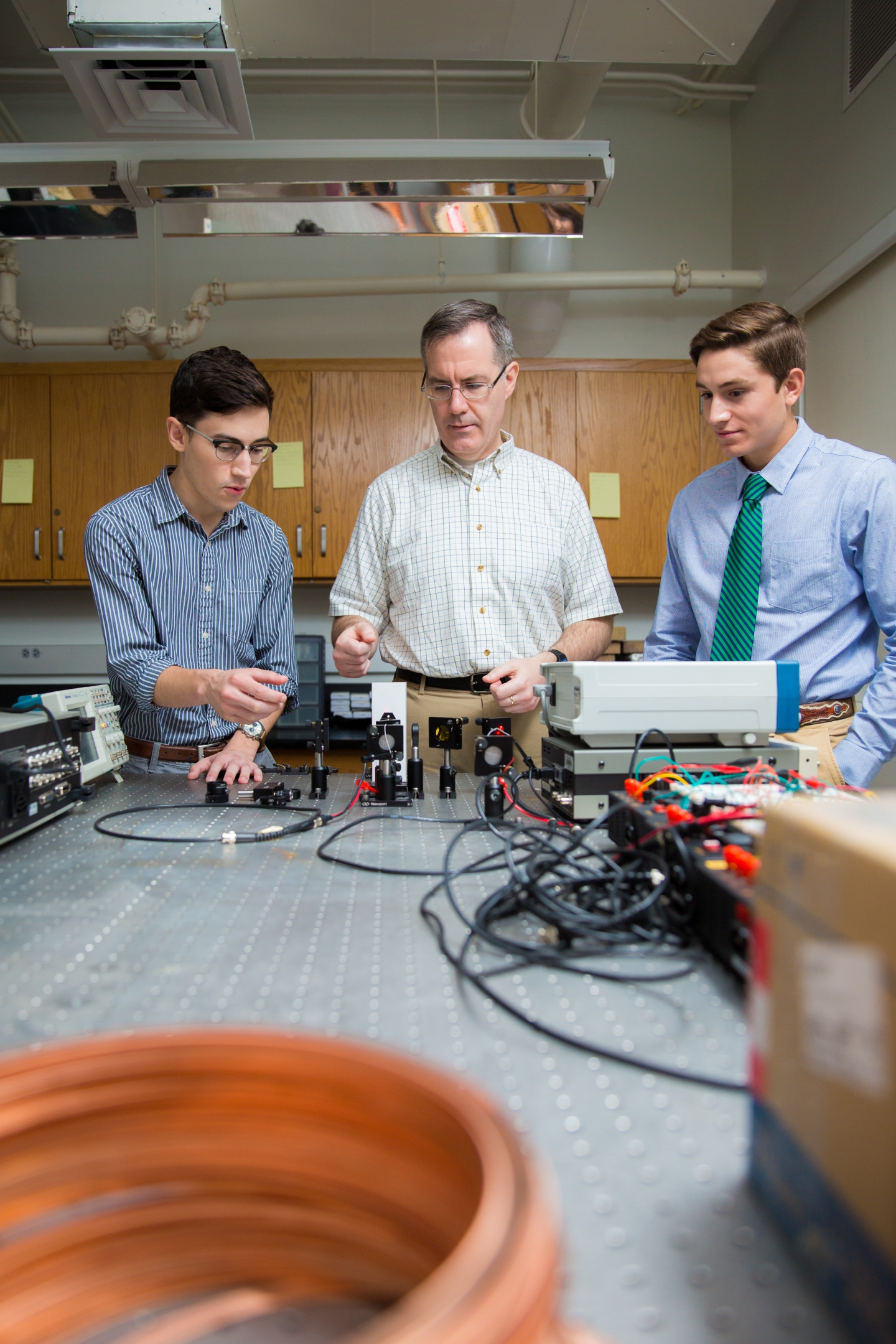 Professor and two male students using equipment