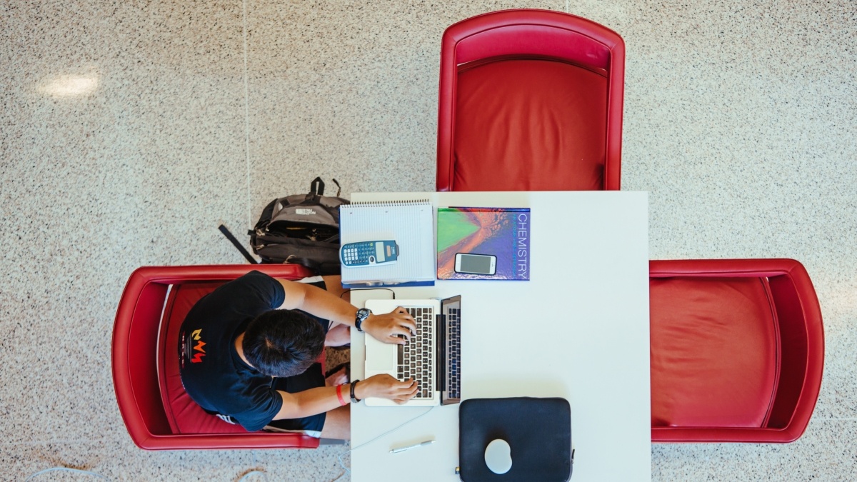 Overhead view of student at table working on computer