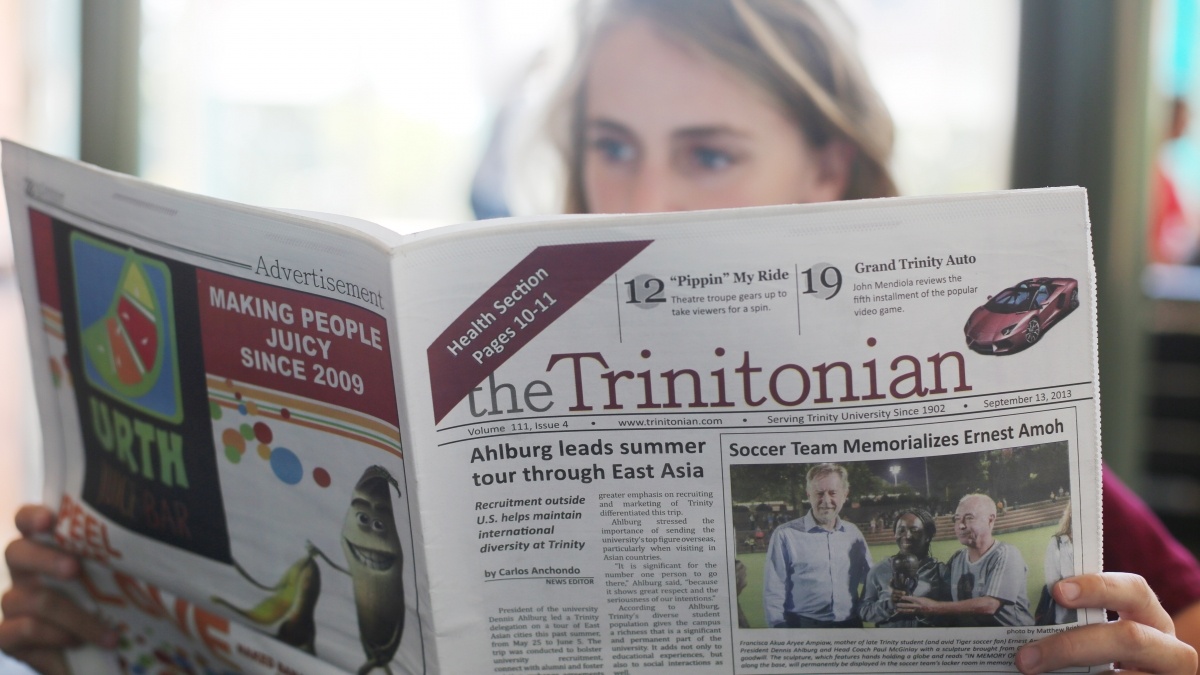 Student reading Trinitonian newspapper