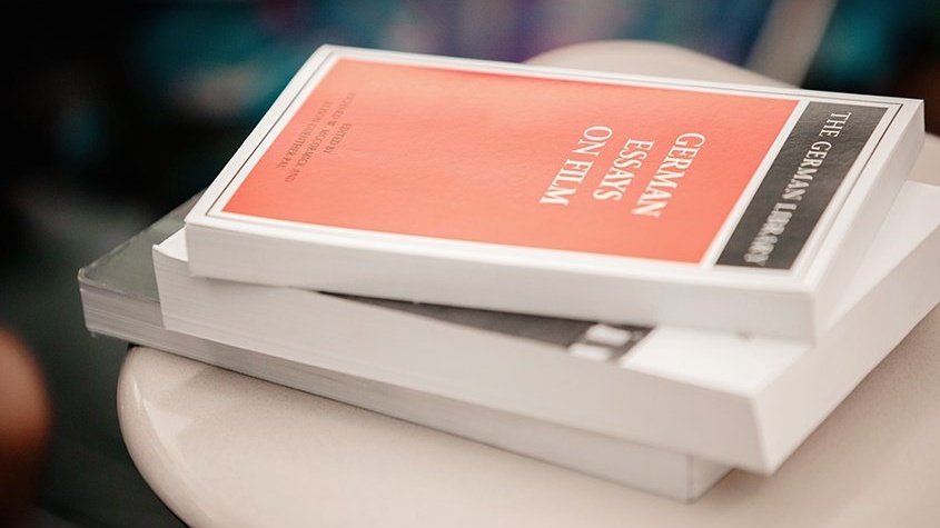 A book, "German Essays on Film" sits on a table