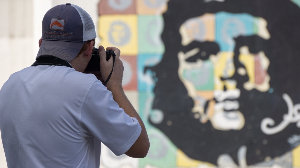 Man takes photo of Che Guevara mural in Cuba.