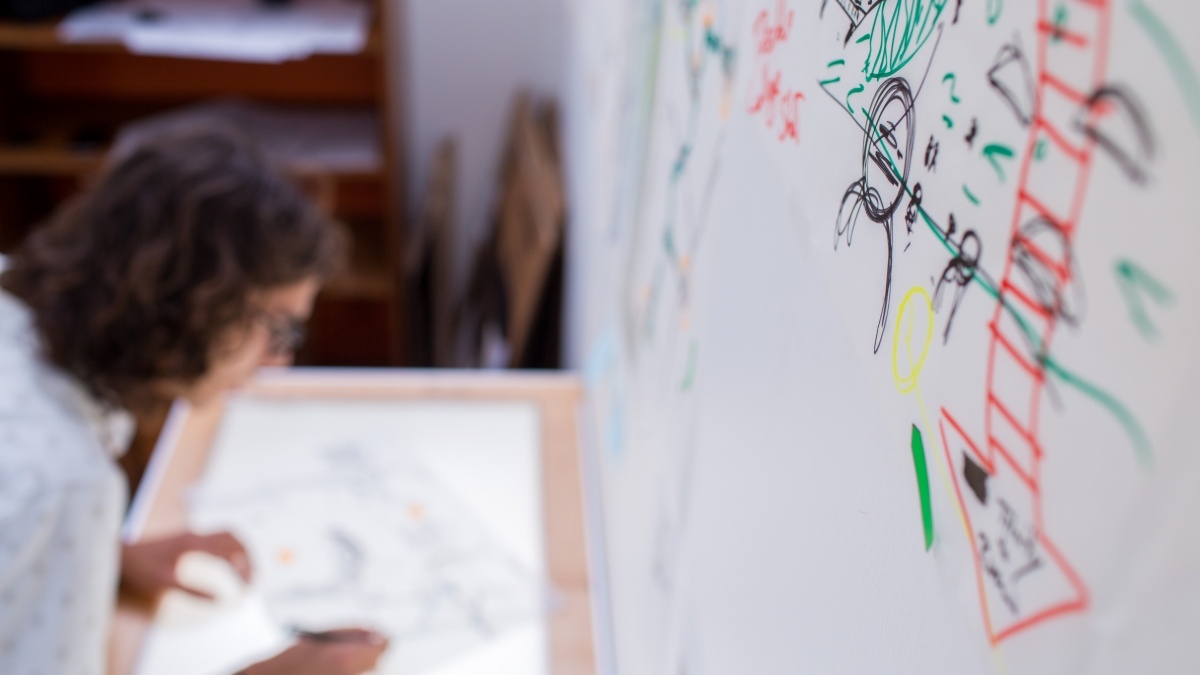 student drawing on a light box with a white board in the background
