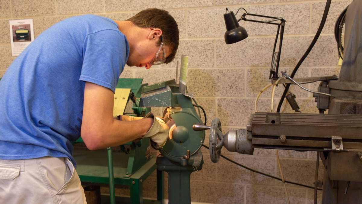 Student working in machine shop creating an object
