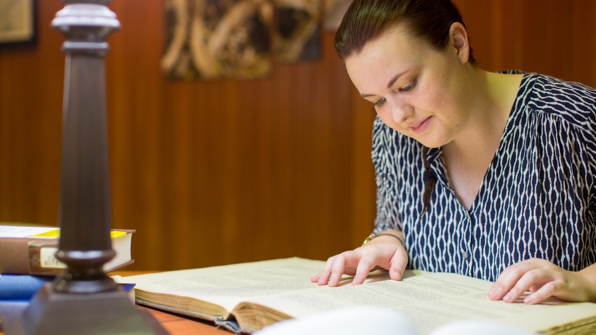 Woman reading book while seated at desk
