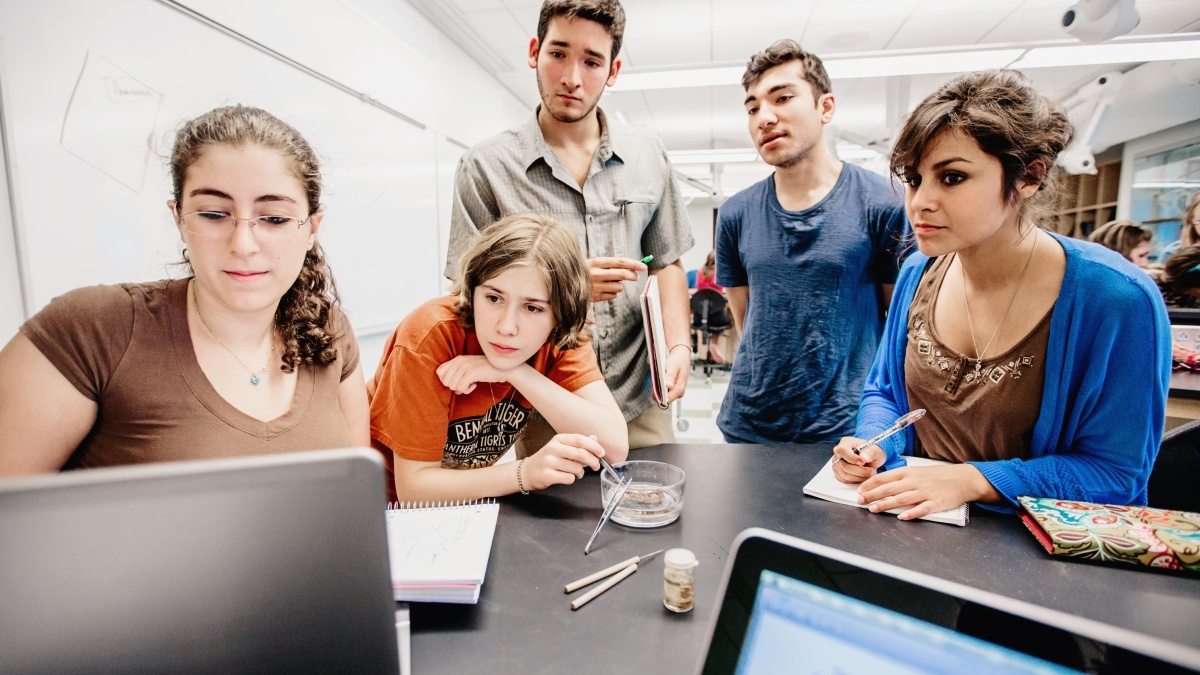 students gather around a table in a lab