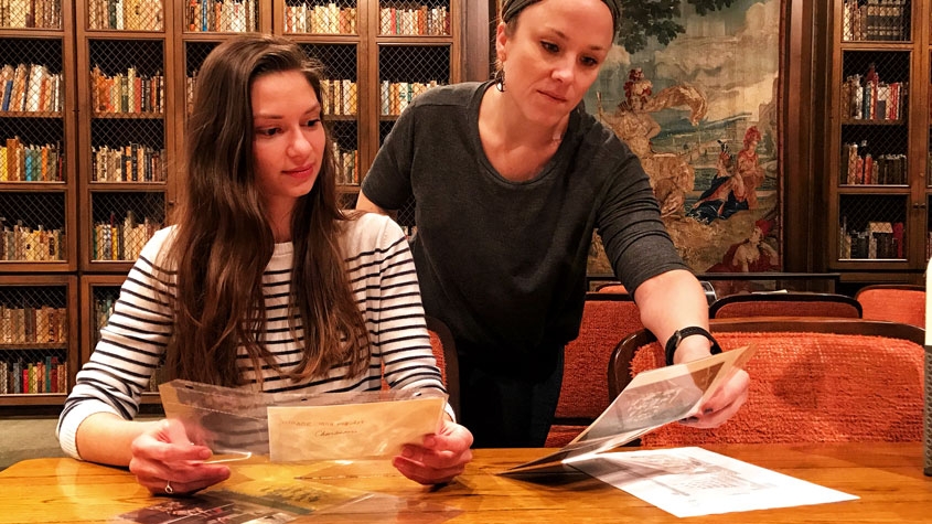 Two people look at articles from the Trinity Archives