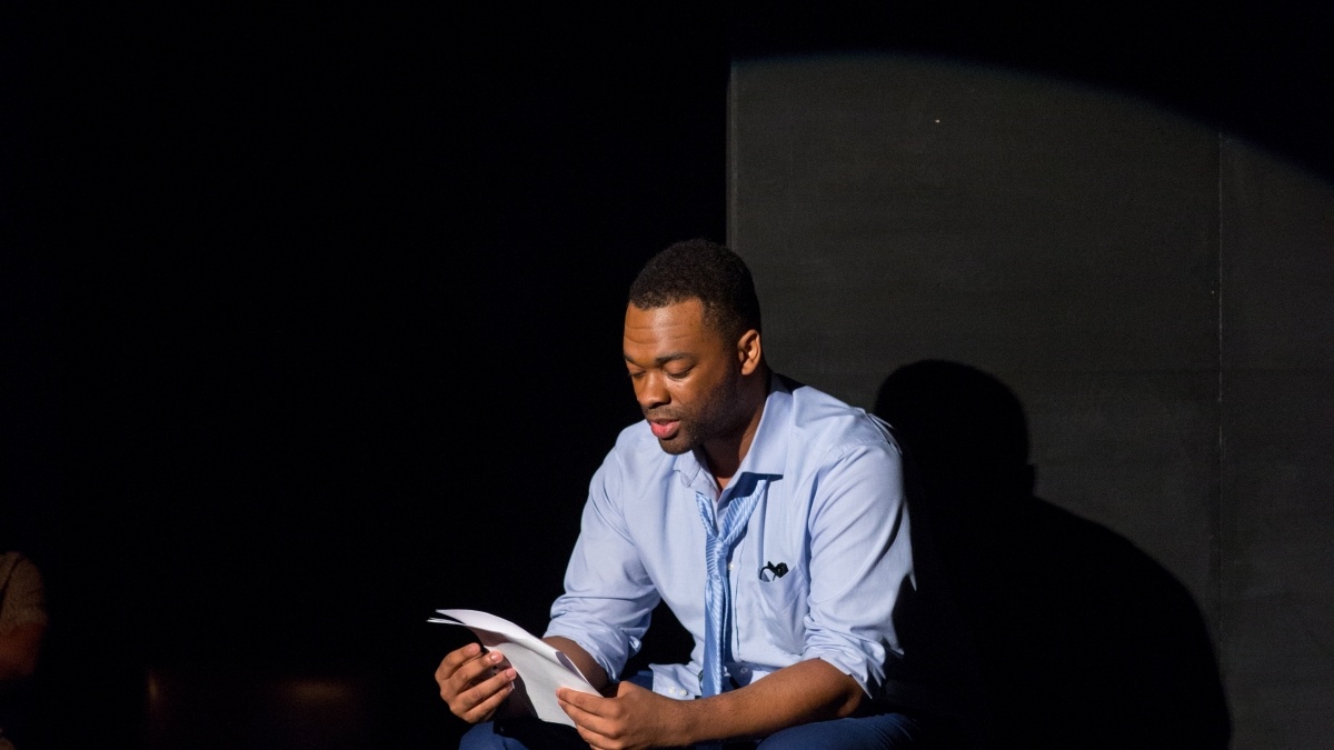 black man sitting in a chair and reading a book