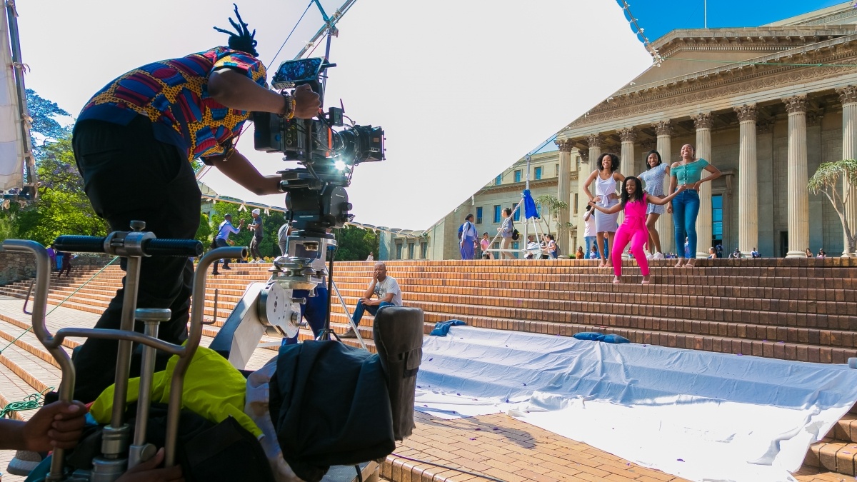 student in a director seat filming a group