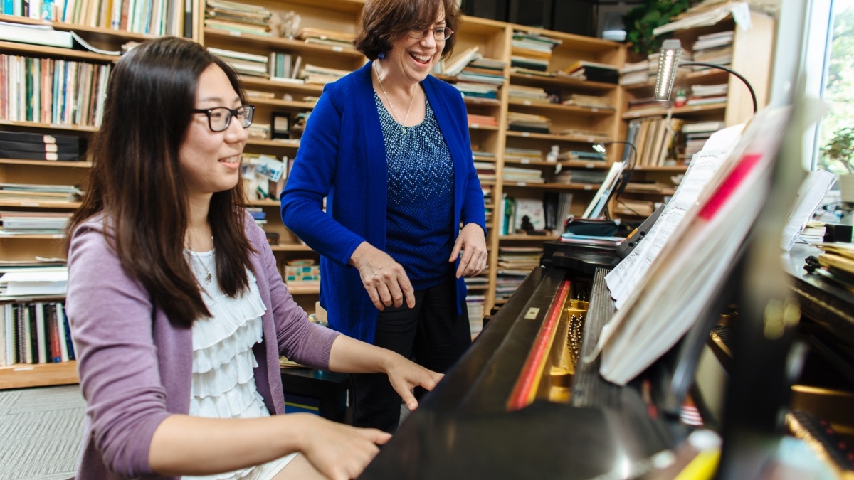 Professor works with student learning piano