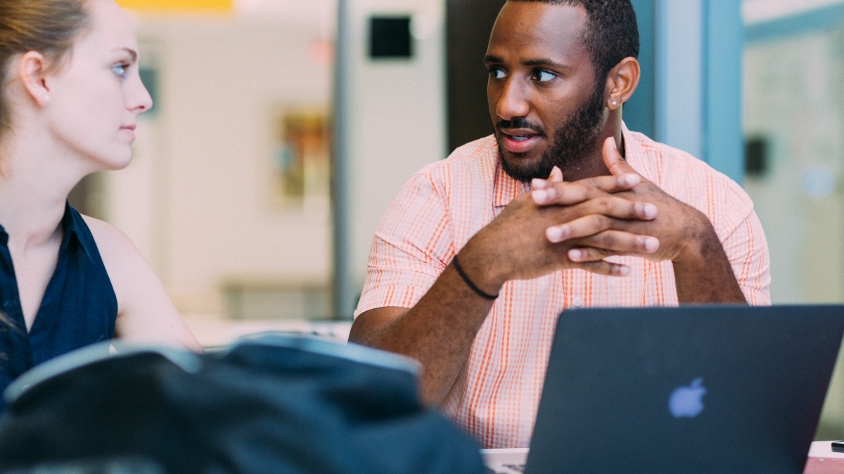Two students at laptops having a discussion